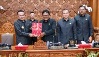 Pjs. Wali Kota Denpasar, I Dewa Gede menyerahkan dokumen Raperda dalam Sidang Paripurna DPRD Kota Denpasar, Senin (18/11/2024). Foto: dok/Pemkot Denpasar