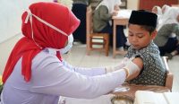 petugas kesehatan memberikan vaksin campak kepada siswa sekolah dasar dalam program imunisasi anak