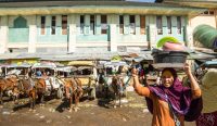 Warga membawa barang belanjaan di kawasan pasar tradisional Indonesia di tengah tekanan ekonomi dan kenaikan biaya hidup.