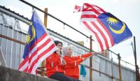 Dua gadis Malaysia mengibarkan bendera nasional di ruang terbuka sebagai simbol semangat dan optimisme masyarakat di tengah tantangan ekonomi global.