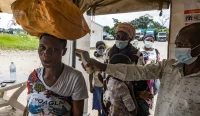 Petugas kesehatan memeriksa suhu tubuh pelintas perbatasan antara Uganda dan Republik Demokratik Kongo di tengah wabah Ebola.