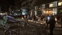 Warga Palestina memeriksa lokasi bangunan yang hancur akibat serangan udara Israel di Gaza City.