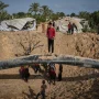 Warga Palestina memeriksa puing-puing bangunan yang hancur akibat serangan udara Israel di Khan Younis, Jalur Gaza selatan.