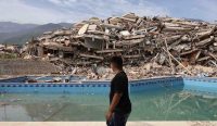 Judul empa Venezuela menghancurkan bangunan di La Guaira, sementara seorang warga melintas di antara puing-puing akibat gempa dahsyat yang menewaskan ratusan orang.