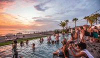 Wisatawan menikmati liburan di pantai Bali saat matahari terbenam, ilustrasi penggunaan serum vitamin C dan sunscreen untuk melindungi kulit dari paparan sinar UV.