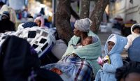 Kekerasan Anti-Imigran di Afrika Selatan memaksa seorang perempuan menggendong bayinya menunggu bus evakuasi di luar Konsulat Malawi di Johannesburg.