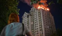 Rusia Gempur Kyiv: Seorang warga menyaksikan kobaran api yang melalap gedung apartemen setelah serangan rudal Rusia menghantam ibu kota Ukraina.