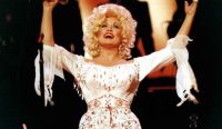 Potret ikonis Dolly Parton bernyanyi di atas panggung dengan gaun putih berumbai. Momen kenangan emas sang Ratu Musik Country yang baru saja tutup usia.