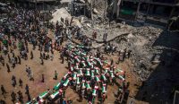 Warga Palestina membawa puluhan peti jenazah korban serangan Israel melewati reruntuhan bangunan di Deir al-Balah, Gaza, menuju pemakaman massal.