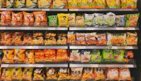 Rak supermarket berisi makanan ultra-proses seperti keripik dan camilan kemasan yang disorot WHO dalam isu obesitas global