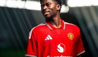 Carlos Baleba tersenyum bangga mengenakan jersey merah Manchester United usai Setan Merah resmi merampungkan Transfer Carlos Baleba senilai triliunan rupiah.