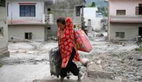 otret pilu seorang wanita berjalan tanpa alas kaki membelah lautan lumpur sambil menggotong koper dan tas berisi sisa harta bendanya paska diterjang banjir bandang.