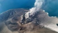 Pemandangan udara kawah Gunung Anak Krakatau yang mengepulkan asap tebal ke langit. Muntahan material ini memicu dampak abu vulkanik mematikan yang berpotensi mencekik tanaman dan memicu gagal panen. (Kredit Foto: Kementerian ESDM)