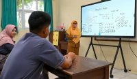 Seorang guru SMAN 14 Bandar Lampung sedang mengajar siswa menggunakan layar cerdas Interactive Flat Panel. Fasilitas digital yang modern ini diharapkan semakin merata di seluruh sekolah melalui program Pendidikan Gratis Prabowo.