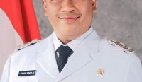 Potret resmi I Komang Koheri mengenakan Pakaian Dinas Upacara berwarna putih lengkap dengan atribut kepala daerah. Sosok I Komang Koheri dikenal sebagai anak transmigran Bali yang sukses menapaki karir politik dari bawah hingga dipercaya menjabat sebagai Plt Bupati Lampung Tengah. (Kredit Foto: Dok. Pemkab Lampung Tengah)
