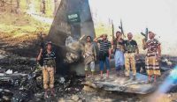 Sekelompok milisi bersenjata berpose di depan puing jet tempur F-15 Arab Saudi yang jatuh, mencerminkan eskalasi ancaman yang memicu kebijakan sekolah Riyadh tutup. Foto: Houthi Group press Service/UPI/Shutterstock.