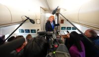 Presiden Donald Trump dikelilingi mikrofon dan kamera wartawan saat berbicara di dalam kabin pesawat Air Force One, sebuah momen akses pers yang kini menjadi sorotan tajam di tengah kontroversi Trump usir media. Foto: Aaron Schwartz/AFP/Getty Images
