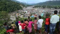Sekelompok warga berdiri di atas bukit menatap sisa-sisa kehancuran lembah di Nuwakot akibat banjir bandang Nepal yang dahsyat. Bencana ini memicu tuntutan ganti rugi iklim kepada negara maju. Foto oleh Sanjit Pariyar/NurPhoto/Shutterstock.