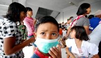 Seorang anak laki-laki memakai masker medis di tengah keramaian untuk mencegah penularan virus influenza. Dokter spesialis menyarankan anak yang sakit untuk beristirahat di rumah dan mengingatkan bahwa penggunaan Oseltamivir untuk flu ringan tidak dianjurkan. (Foto: Kemenkes)