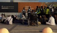 Sekelompok warga dan penumpang telantar duduk lesehan di luar stasiun metro arah Bandara Internasional Raja Khalid, Riyadh, akibat dampak Serangan Rudal Houthi pada hari Sabtu. (Kredit Foto: AP)