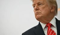 Potret jarak dekat wajah Presiden AS Donald Trump yang menatap dengan ekspresi serius, mengenakan jas hitam dan dasi merah bergaris putih. Keputusan kontroversialnya memborong jutaan ton Solar Rusia memicu kemarahan Presiden Ukraina Zelensky. (Kredit Foto: Kent Nishimura/AFP/Getty Images)