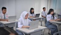 Sejumlah siswa dan siswi berseragam putih abu-abu tampak fokus menatap dan mengetik di layar laptop masing-masing di dalam ruang kelas sebagai bentuk kesiapan menyambut Pendaftaran TKA 2026. Kredit Foto: Dok. Kemendikdasmen.