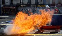 Petugas pemadam kebakaran berusaha memadamkan kobaran api besar di jalan raya saat Demo Pelajar Prancis memanas di dekat SMA Lycée Berthelot, pinggiran Paris. Terlihat barisan polisi anti huru-hara bersiaga di latar belakang. (Foto: Sarah Meyssonnier/Reuters)