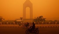 Pengendara motor menembus kabut asap oranye pekat beracun yang menyelimuti kota akibat Bencana Karhutla di Palangka Raya, Kalimantan Tengah, sebuah kondisi krisis yang memicu desakan DPR agar pemerintah segera menetapkan status Bencana Nasional. (Kredit Foto: REINA/AFP/Getty Images)
