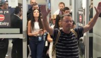 Seorang pria mengangkat kedua tangannya mengekspresikan kelegaan, diikuti rombongan penumpang pesawat flydubai saat tiba di Bandara Ben Gurion, usai selamat dari insiden kopilot tikam pilot. Foto: Ariel Schalit/AP