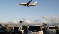 Pesawat jet Angkatan Laut AS terbang rendah bersiap mendarat di atas antrean kendaraan dekat pangkalan udara Kadena, Okinawa, lokasi di mana militer AS resmi memblokir masuknya mobil listrik BYD karena ancaman intelijen. Foto: Andrew Caballero-Reynolds/AFP/Getty Images.