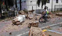 Seorang warga bersepeda melintasi bongkahan pilar dan puing-puing Gereja San Atanasio yang runtuh ke jalanan akibat dahsyatnya Gempa Panama di La Villa de Los Santos. Foto: Bienvenido Velasco/EPA.