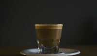 Segelas kopi pekat di dalam gelas kaca berukuran kecil dengan latar belakang gelap. Konsumsi kafein hitam dalam takaran wajar tanpa tumpukan gula adalah kunci utama untuk mendapatkan manfaat kopi untuk liver secara optimal. (Foto: Matt Hoffman/Unsplash). Judul (Title)