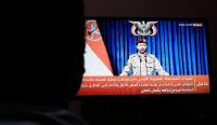 Siluet seseorang sedang menonton siaran televisi yang menampilkan juru bicara militer Houthi, Yahya Saree. Pernyataan dan manuver serangan kelompok pemberontak ini memicu ketegangan baru yang berdampak pada keselamatan dan Kondisi WNI di Arab Saudi. (Kredit Foto: Yahya Arhab/EPA)